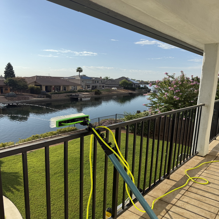 Cleaning glass with a water-fed pole overlooking the water
